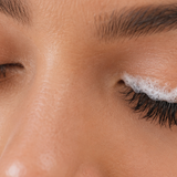 Woman gently cleansing wispy eyelash extensions with foaming lash cleanser and a soft brush.