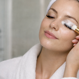 Woman cleaning her lash extensions with a foam cleanser and a brush.